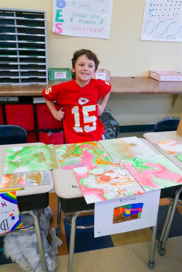 boy at desk with artwork